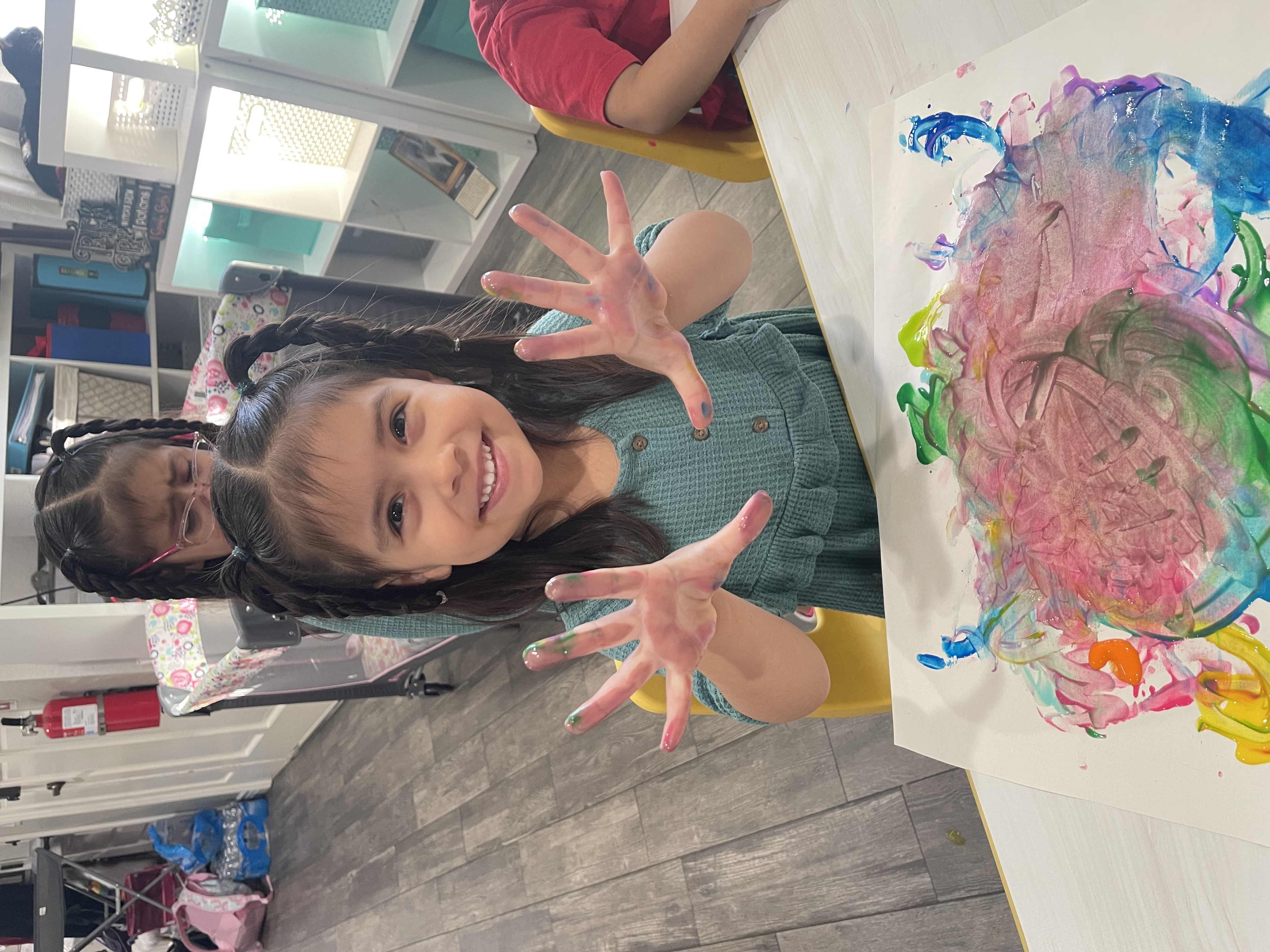 Girl showing paint-covered hands after finger painting
